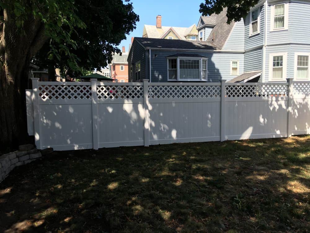 Tan vinyl semi-privacy fence panels installed on a sloped lot.